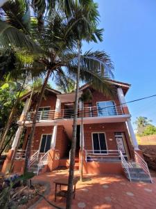 a house with a palm tree in front of it at The Stone Cabin Cottage in Gokarna