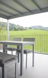 una mesa y sillas en un porche con vistas a un campo en Ferienwohnung Brandholz - b48310, en Ebnat