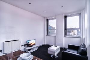 Contemporary 1 Bed Apartment in Central Blackburn في بلاكبيرن: غرفة معيشة بها أريكة وتلفزيون و نافذتين