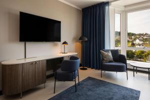 um quarto com uma secretária, uma televisão e 2 cadeiras em Scandic Park Sandefjord em Sandefjord