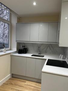 una cucina con armadi bianchi, lavandino e finestra di Dralda House a Buckinghamshire