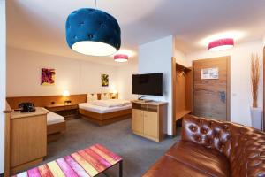 um quarto de hotel com um sofá e uma televisão em Hotel Pension Kirchplatz em Sankt Anton am Arlberg