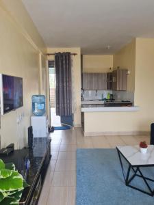 a living room with a table and a kitchen at La Ribera Cosy Homes in Bomet