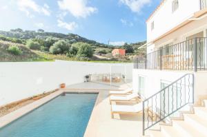 een zwembad aan de zijkant van een wit huis bij Casa Lluminosa, fabulosa y moderna casa de pueblo by Sonne Villas in Ferreries