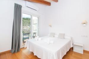 een witte slaapkamer met een bed en een groot raam bij Casa Lluminosa, fabulosa y moderna casa de pueblo by Sonne Villas in Ferreries