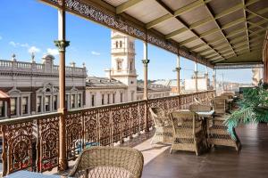 a balcony with chairs and a table and a building at Quality Inn The George Hotel Ballarat in Ballarat