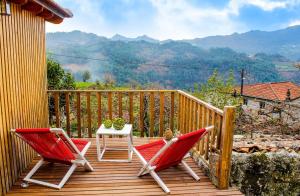 due sedie rosse e un tavolo su una terrazza di legno di Villa Garcia a Terras de Bouro