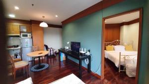 a room with a bed and a table and a kitchen at Cozy 1br walk to BTS and Airport Rail Link Close to Malls G7 in Bangkok