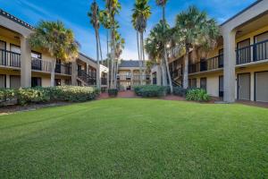 a large yard in front of a building with palm trees at Quality Inn Orange Park Jacksonville in Jacksonville
