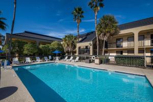 a swimming pool in front of a hotel with palm trees at Quality Inn Orange Park Jacksonville in Jacksonville