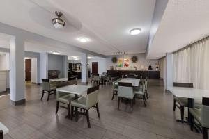 a dining room with tables and chairs and a kitchen at Quality Inn Orange Park Jacksonville in Jacksonville