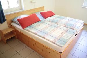イルセンブルクにあるFerienwohnung Ferienhäuser am Brocken, 60 qm 2 Schlafzimmerの木製ベッド(赤い枕2つ付)