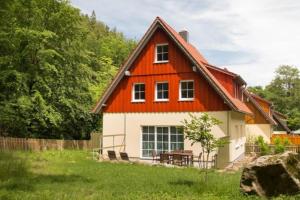 une maison rouge et blanche avec une table dans une cour dans l'établissement Ferienhäuser Ilsestein Einzelhaus, 130 qm, 4 Schlafzimmer, à Ilsenburg