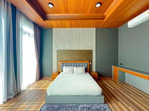 a bedroom with a large bed with a wooden ceiling at Villa Menara Bang Tao in Phuket Town