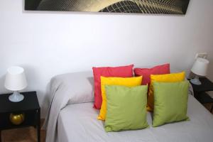 ein Bett mit bunten Kissen darüber in der Unterkunft Habitaciones con cama de matrimonio en Mislata by Alterhome in Valencia