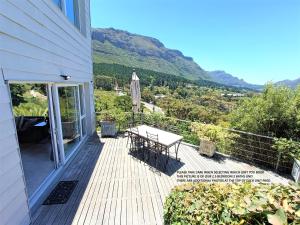 a wooden deck with a table and an umbrella at Mount Rhodes Guesthouse, three separate units, please select either three bedroom, two and a half bedroom or one bedroom in Cape Town