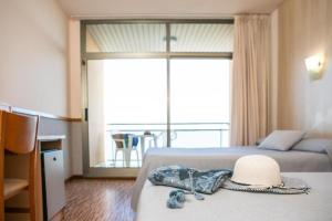 una habitación de hotel con 2 camas y un sombrero en la cama en RVHotels Hotel Ametlla Mar, en L'Ametlla de Mar