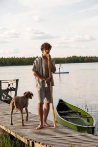 a man standing on a dock with a dog and a boat at Metsä Kolo in Saariharju
