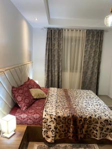 Un dormitorio con una cama y una ventana con cortinas. en Résidence palmerie, en La Marsa