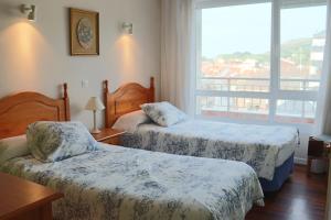 ラレードにあるApartamento Laredoのベッドが2つと窓があるホテルの部屋