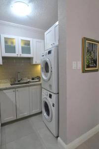una cocina blanca con lavadora y secadora. en Secluded Ravinia Gem in Kingston 6, en Kingston
