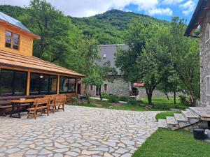 un patio con mesa y bancos y un edificio en Villa Gjeçaj Guesthouse and Restaurant, en Theth