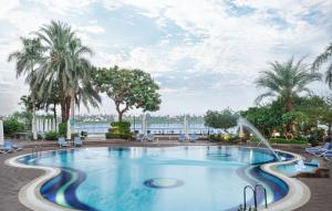 a swimming pool with palm trees and a fountain at Steigenberger Nile Palace Luxor - Convention Center in Luxor