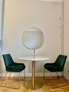 une table avec deux chaises vertes et un miroir dans l'établissement Yksiö Punavuoresta, à Helsinki