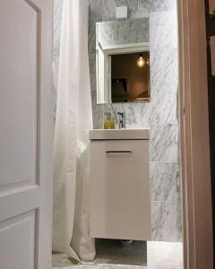 La salle de bains blanche est pourvue d'un lavabo et d'un miroir. dans l'établissement Yksiö Punavuoresta, à Helsinki