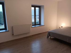 an empty room with a bed and two windows at Gîte des Sagards in Saint-Michel-sur-Meurthe