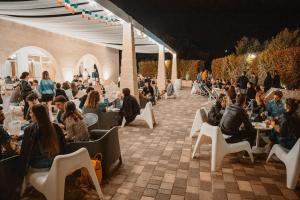 un groupe de personnes assises à des tables dans un patio la nuit dans l'établissement Agriturismo Ciriè, à Cassano delle Murge