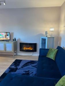 a living room with a blue couch and a fireplace at Central Tetbury Apartment 