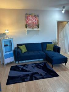 a living room with a blue couch and a rug at Central Tetbury Apartment 