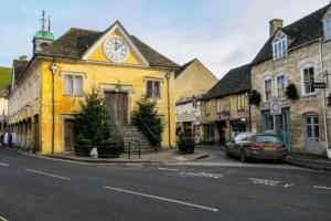 a yellow building with a clock on it on a street at Central Tetbury Apartment 