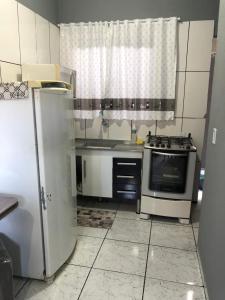a kitchen with a refrigerator and a stove top oven at Kitnet do Costa Praia do Pereque Guaruja!!! in Guarujá