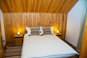 a bedroom with a large white bed with wooden walls at Cabana din poiană in Câmpulung Moldovenesc