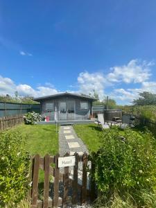 AmlwchにあるGlamping Huts x 3 and a Static Caravan available each with a Private Hot Tub, FirePit, BBQ and are located in a Peaceful setting with Alpacas and gorgeous countryside views on Anglesey, North Walesの前に柵のある家