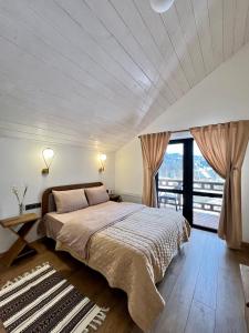 a bedroom with a large bed and a large window at Villa Pelahia in Slavske