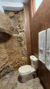 een stenen badkamer met een toilet en handdoeken bij Rock n Fall Nature Resort in Ella