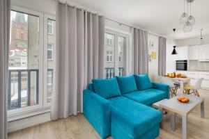 uma sala de estar com um sofá azul e uma grande janela em Bulwar Piastowski Chic Apartment em Szczecin