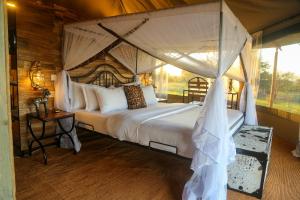 een slaapkamer met een groot bed met een baldakijn bij Ndoto Serengeti Camp in Serengeti