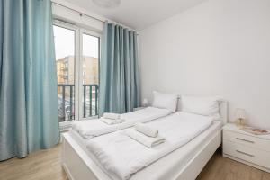 um quarto branco com uma grande janela com cortinas azuis em Bulwar Piastowski Chic Apartment em Szczecin