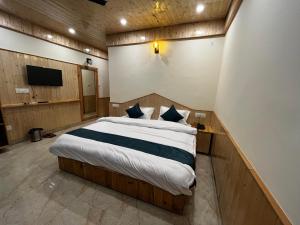 a bedroom with a bed and a tv in it at Hotel Mid Orchard Kasol l River Side in Kasol