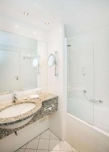 a bathroom with a sink and a shower at ARCOTEL Castellani Salzburg in Salzburg