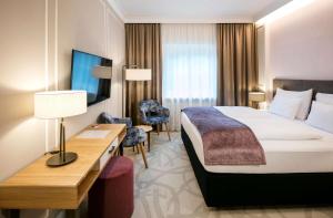 um quarto de hotel com uma cama e uma secretária em ARCOTEL Castellani Salzburg em Salzburgo
