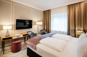 a hotel room with a bed and a desk and a television at ARCOTEL Castellani Salzburg in Salzburg