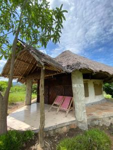 une maison avec deux chaises et un toit de chaume dans l'établissement Eco Mara Tented Camp, à Ololaimutiek 28 autres photos