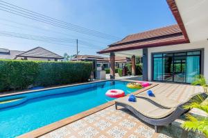 a swimming pool with two chairs and a house at Villa ABBIE ! Amazing Pool Villa for family and Friends in Hua Hin