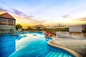 a large swimming pool with a sunset in the background at JA Hatta Fort Hotel in Hatta