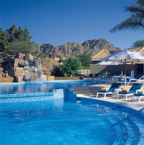 einen großen Pool mit Stühlen und einem Wasserfall in der Unterkunft JA Hatta Fort Hotel in Hatta